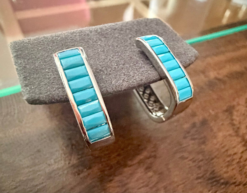 Turquoise inlay sterling silver hoop earrings displayed on a jewelry stand