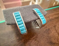 Turquoise inlay sterling silver hoop earrings displayed on a jewelry stand